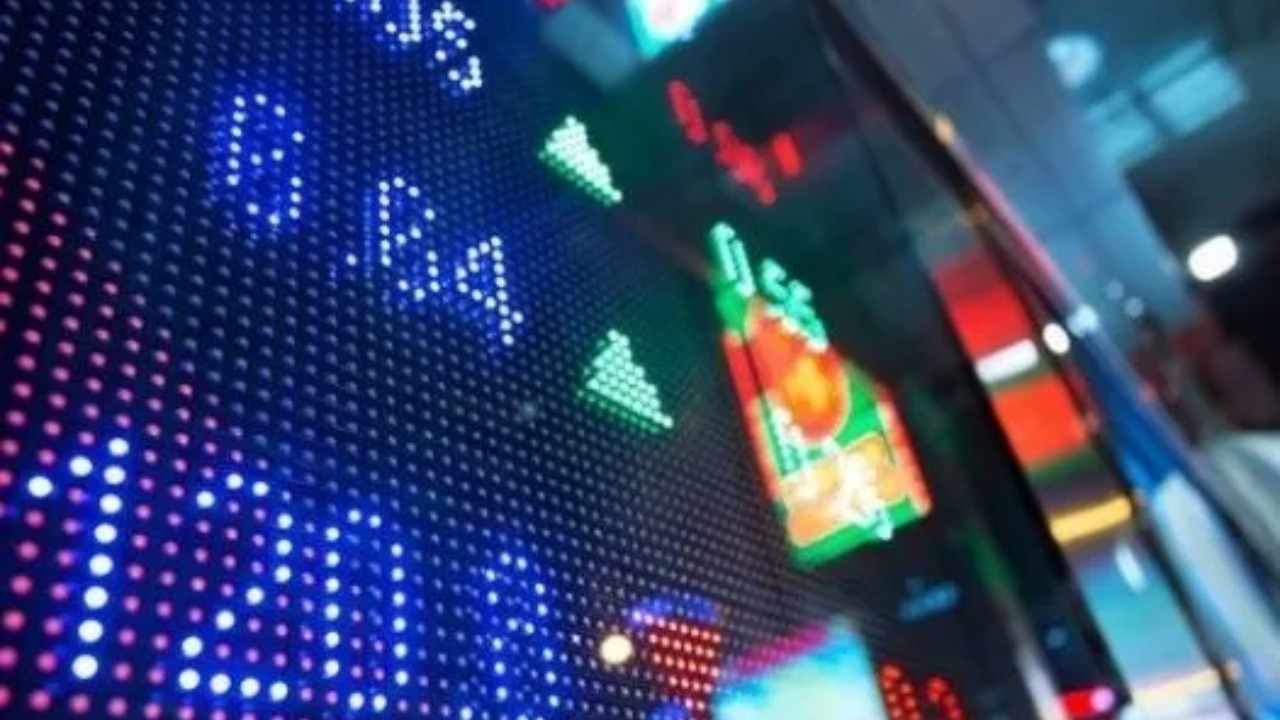 Stock market display board showing colorful numbers, arrows and financial indicators.