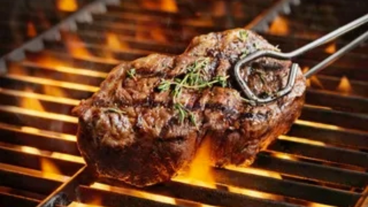 Grilled steak cooking over an open flame on a barbecue grill.