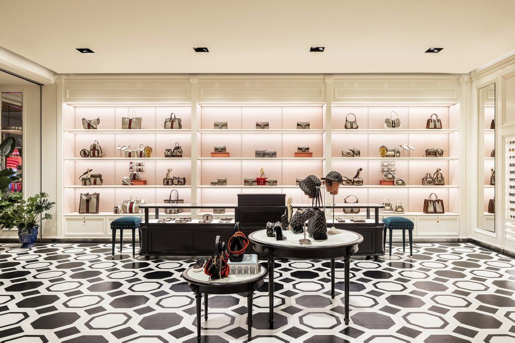Gucci boutique interior featuring handbags on wall displays, round display tables and geometric black-and-white flooring.