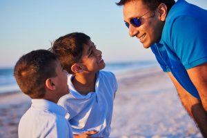 Shilen Patel and his two sons smiling while on a beach