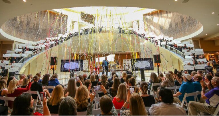Crowd gathered inside Seminole Hard Rock Hotel and Casino Tampa as 75 local charities receive $10,000 checks during a National Philanthropy Day celebration with confetti falling from above.