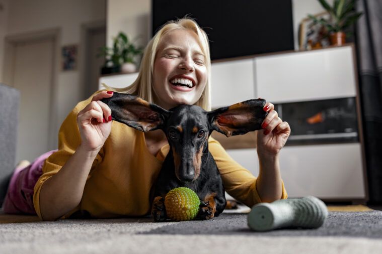 Caucasian woman and cute dog having fun together at home