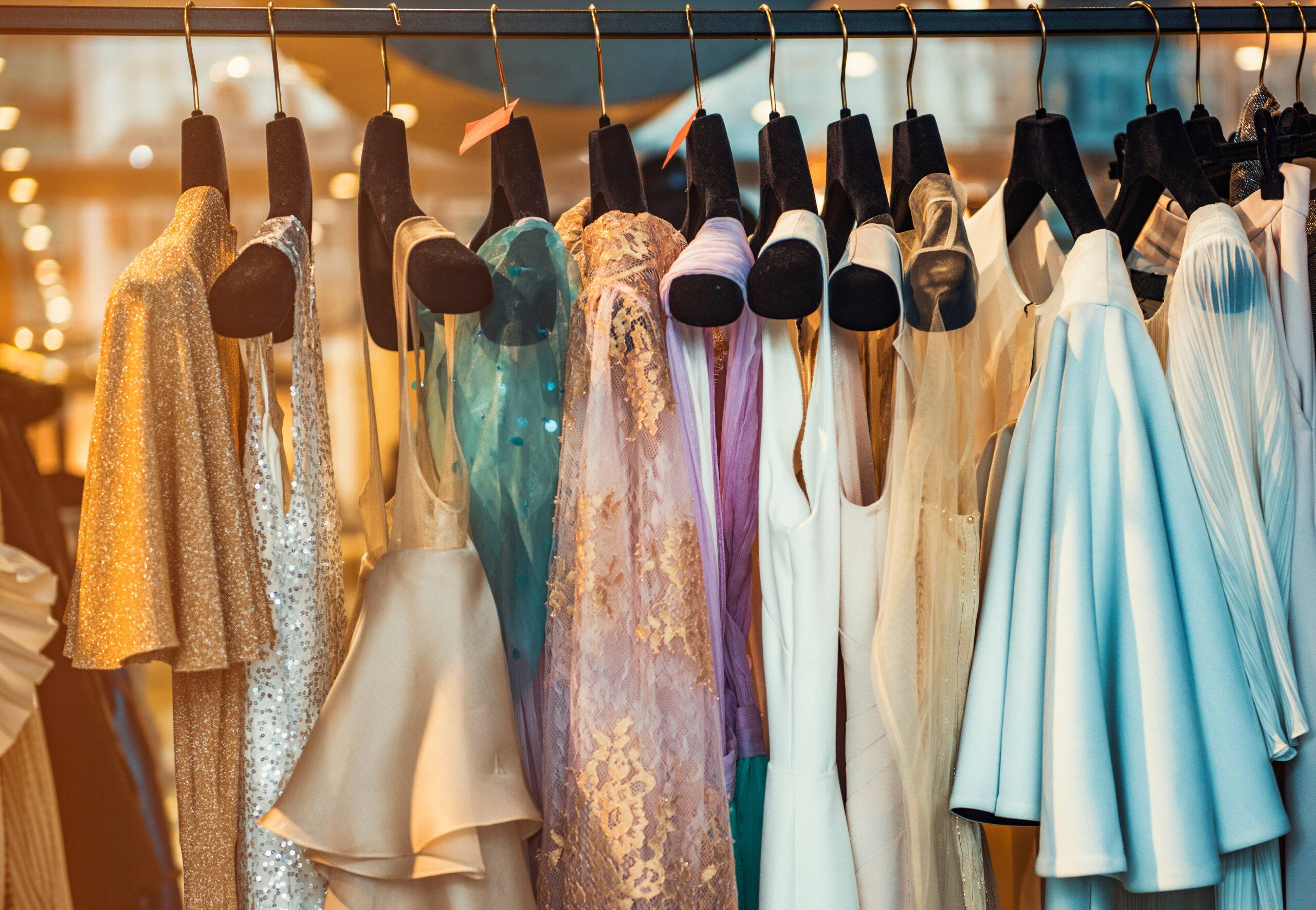 Elegant gowns in shades of gold, lavender and blue hang on a rack, showcasing luxury fashion ahead of the “Passport to Paris” charity event in downtown St. Petersburg.
