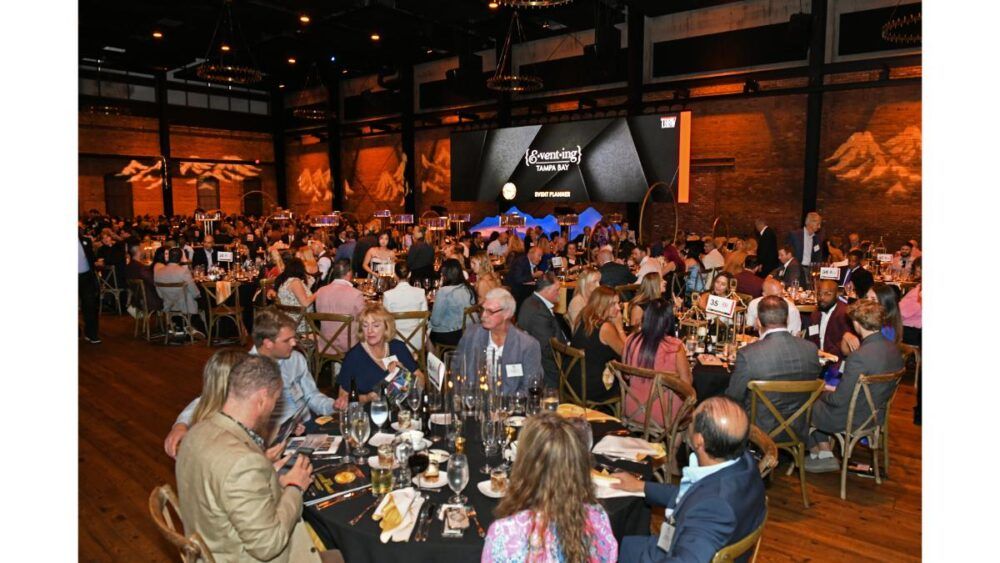 Guests seated at banquet tables during the TBBW Apogee Awards ceremony, with the stage and event screen visible in the background.