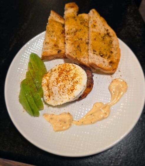 Poached egg over a shrimp cake with Old Bay aioli, avocado slices and toasted bread.