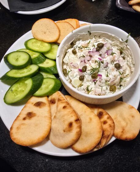 Smoked salmon dip with cream cheese, dill, capers and red onion, served with cucumbers, crostini and flatbread.