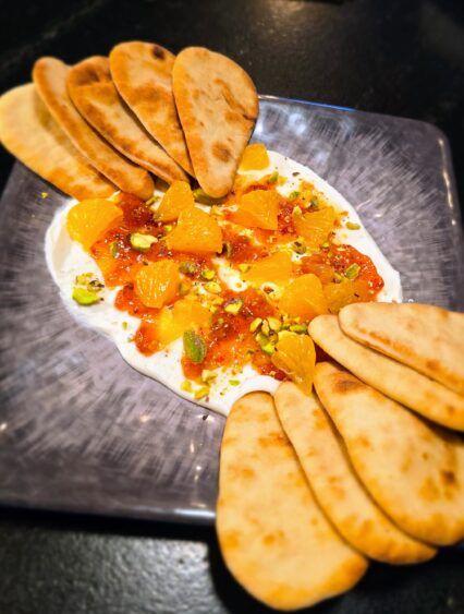 Sweet Heat Whipped Cheese topped with oranges, pistachios and Calabrian jam, served with warm flatbread.