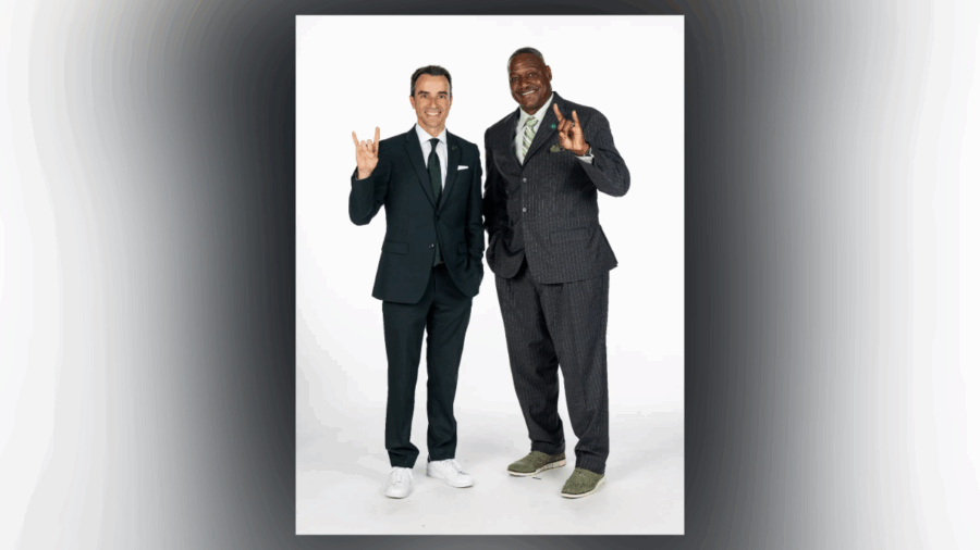 Rob Higgins and Derrick Brooks pose together, both wearing suits and making the USF Bulls hand sign to celebrate Brooks’ new role as chief operating officer of USF Athletics.
