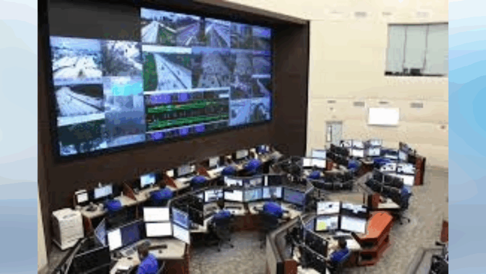 Staff monitor live traffic feeds and data inside Tampa’s Traffic Management Center, surrounded by large wall screens and multiple computer stations.