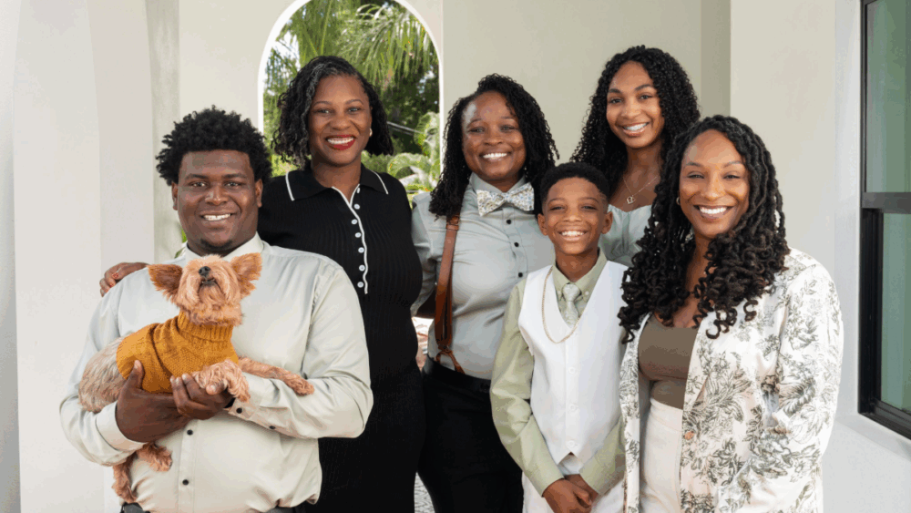 Ashley Butler and her wife, Adrien, smiling with their family and dog at their Tampa home.
