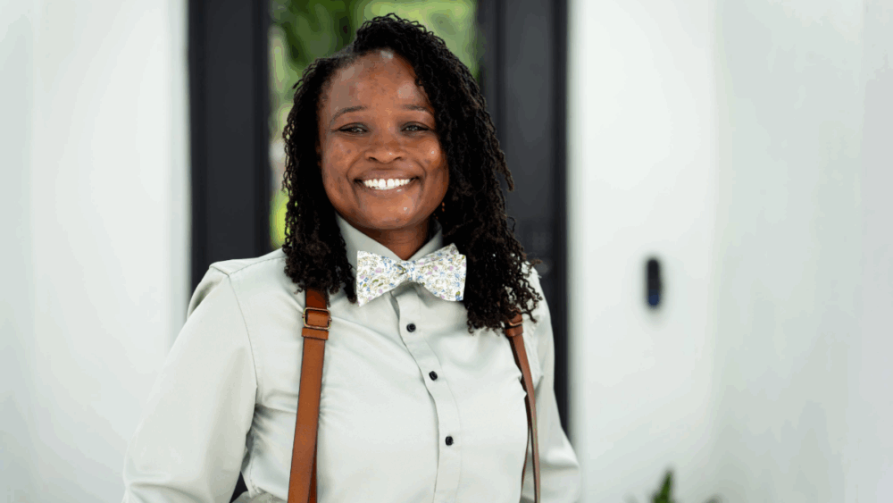 Ashley Butler smiling in a bow tie and suspenders at her Tampa home.
