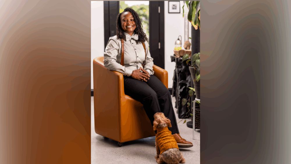 Ashley Butler sitting in a chair with her dog nearby inside her Tampa home.