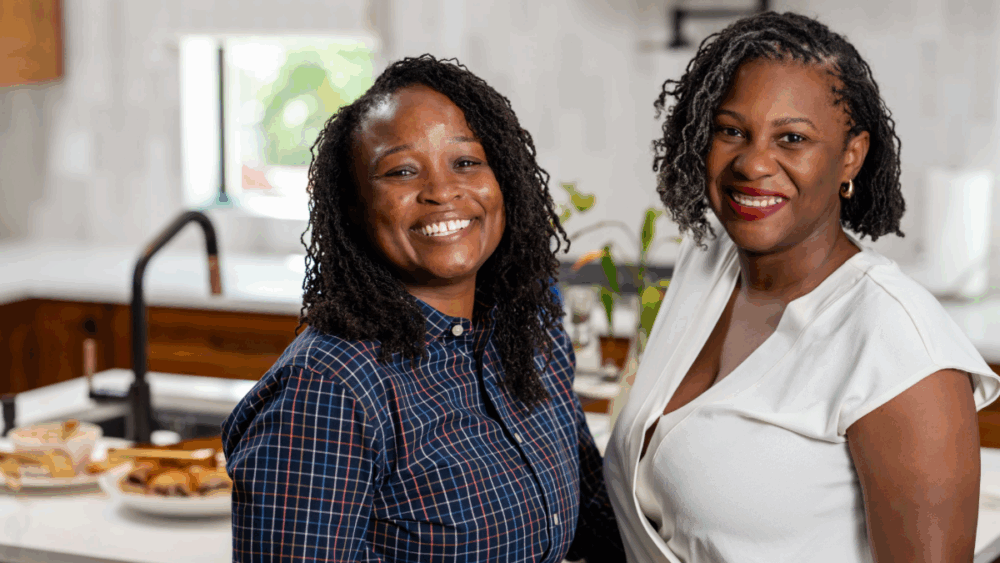 Ashley Butler and her wife, Adrien, smiling together in the kitchen of their Tampa home.