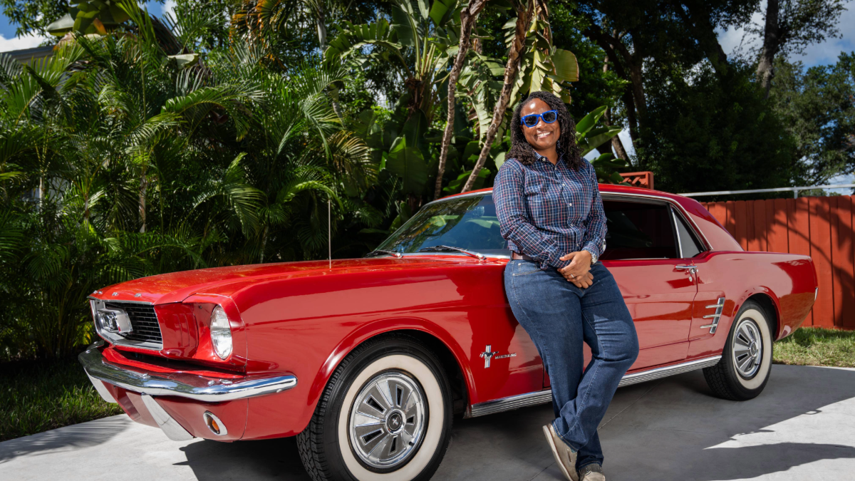 Ashley Butler, owner of Ice Cold Air, standing beside a red Ford Mustang at her Tampa home.