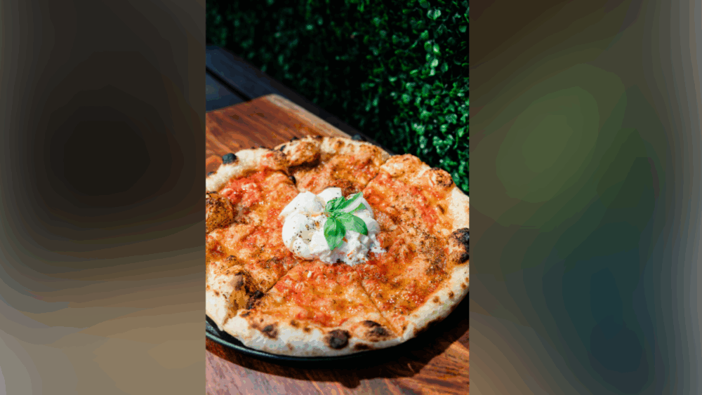 Close-up of Che Vita’s Rossa Moderna pizza topped with burrata and basil on a wooden table in downtown Tampa