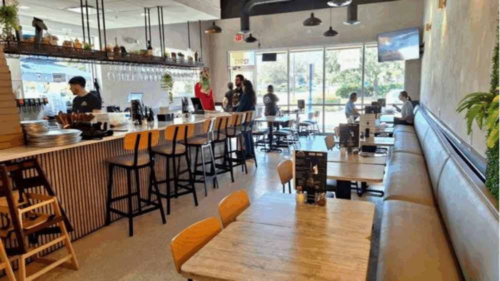Interior view of Sogna Napoli restaurant in Carrollwood with tables, bar seating and natural light from large front windows.