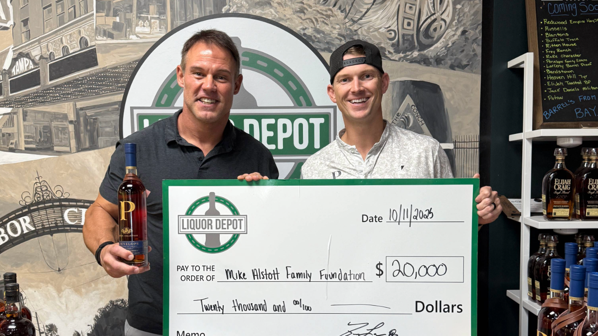 Liquor Depot owner Trey Lawson and former Buccaneers player Mike Alstott present a $20,000 check to the Mike Alstott Family Foundation at Liquor Depot’s Waters Avenue location in Tampa.