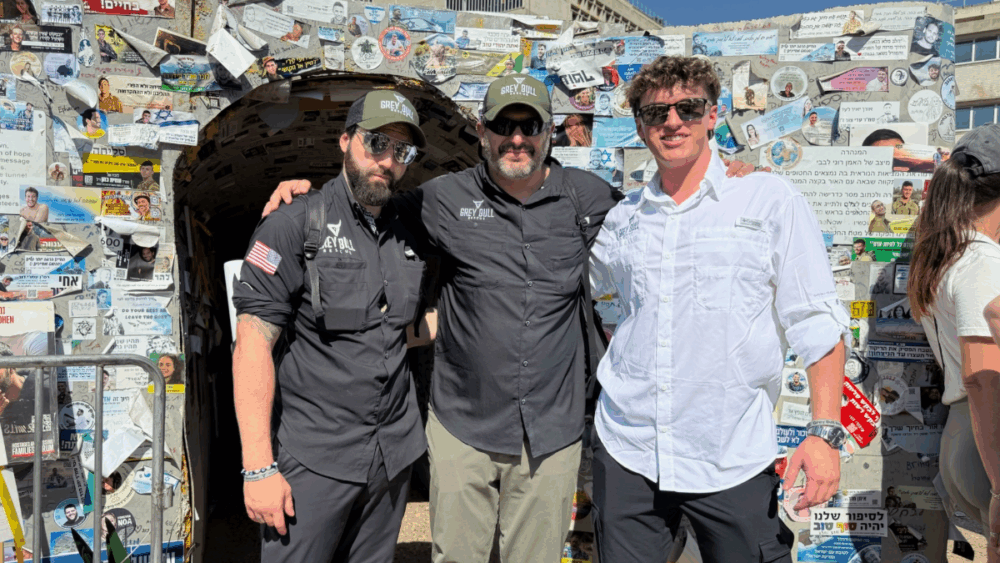 Bryan Stern, founder of Tampa-based Grey Bull Rescue, stands with team members at Hostages Square in Tel Aviv in front of a wall covered with photos and notes honoring hostages and fallen soldiers.