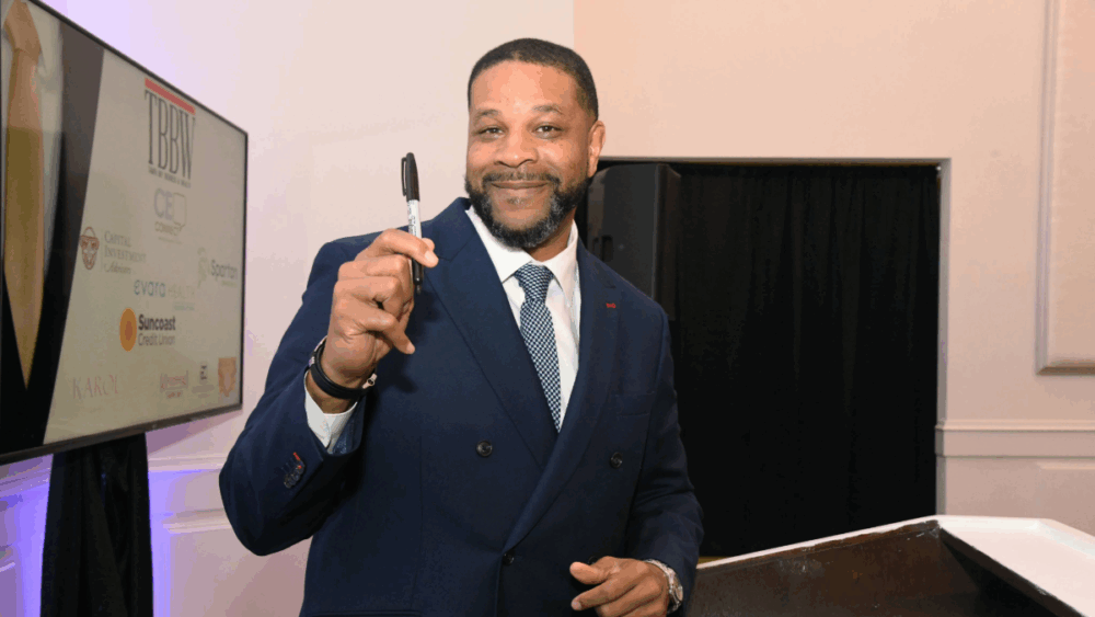 Gary Hartfield holds a pen in the air at Tampa Bay Business & Wealth's CEO before signing his cover.