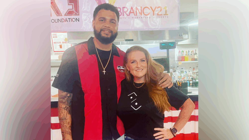 Teal Henderson standing beside Buccaneers wide receiver Mike Evans at a community event.