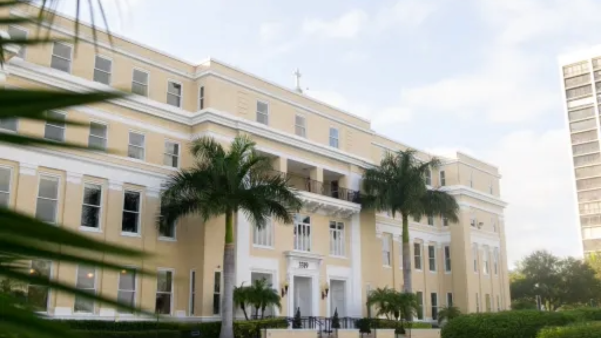 The front entrance of the Academy of the Holy Names on Bayshore Boulevard in South Tampa, framed by palm trees and early morning light.