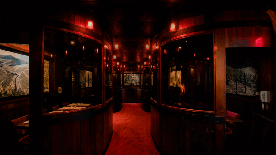Interior view of the Harry Waugh Dessert Room at Bern’s Steak House, showing private redwood booths and soft red lighting.