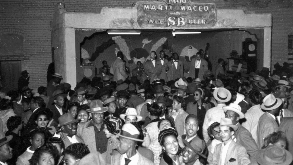 Archival photo of a lively crowd gathered inside Tampa’s historic Marti-Maceo Club in Ybor City, with musicians performing on stage.