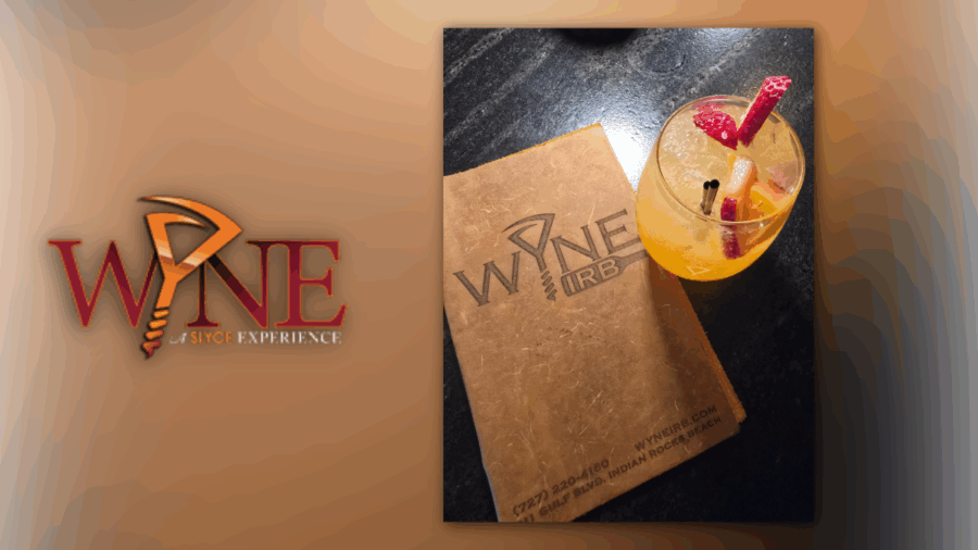 Wyne IRB logo with a leather-bound menu and a white sangria garnished with fruit, photographed on a black table.