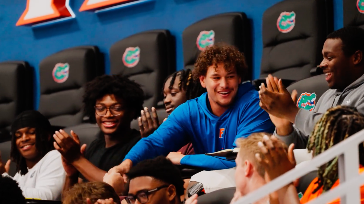 University of Florida football player Charles Emanuel III smiles and shakes hands with teammates as they applaud during a team meeting.