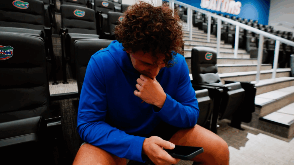 University of Florida football player Charles Emanuel III sits in the team’s film room, speaking on the phone after receiving the news of his scholarship.