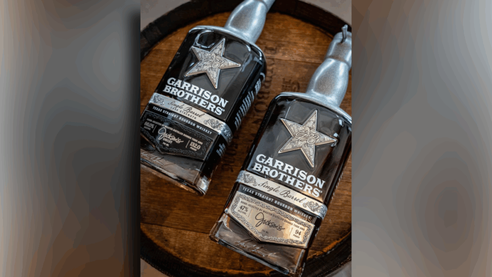 Two bottles of Garrison Brothers Single Barrel Texas Straight Bourbon Whiskey sit on a wooden barrel.