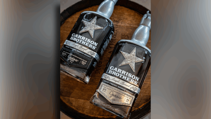 Two bottles of Garrison Brothers Single Barrel Texas Straight Bourbon Whiskey sit on a wooden barrel.