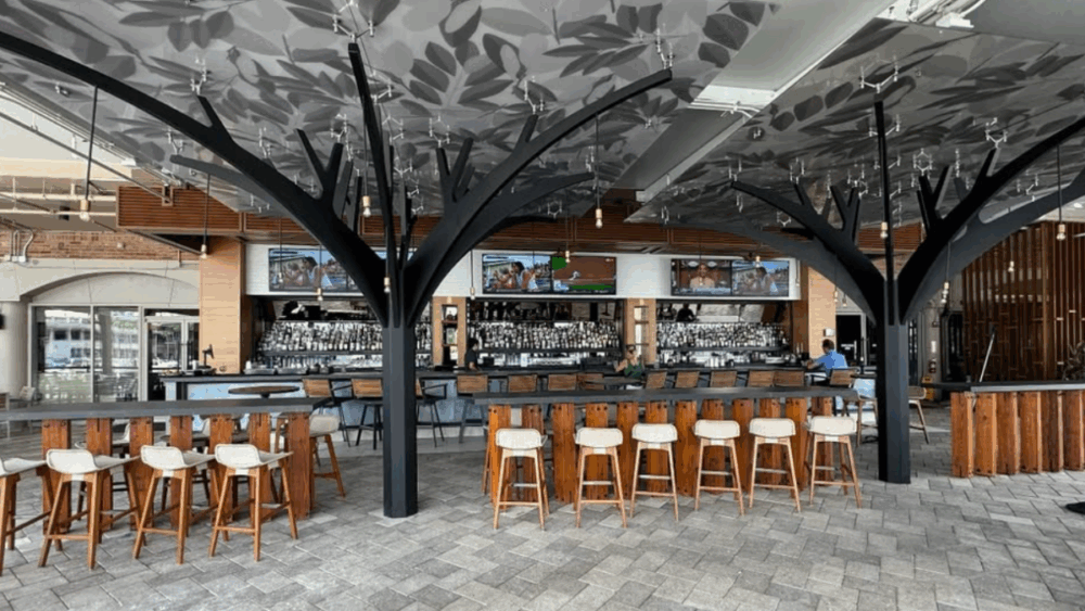 A spacious bar area with tree-inspired columns and multiple TV screens at Jackson’s Bistro.