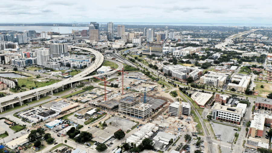 Aerial view of the Gasworx development under construction in Ybor City, with downtown Tampa’s skyline and the Selmon Expressway in the background.