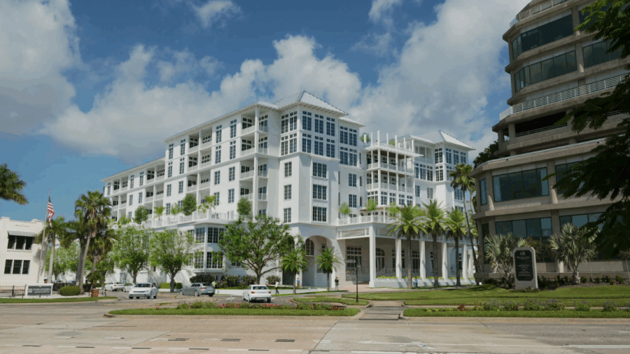 Wide shot of Magnolia Hotel & Residences from Bayshore Boulevard, showing its white façade, balconies and surrounding greenery.