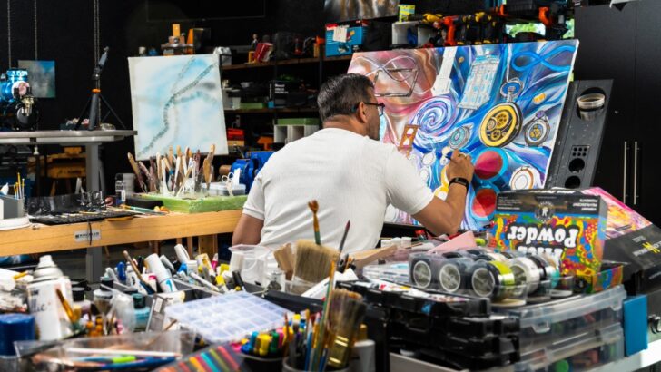 Dr. Ali painting a colorful abstract piece in his home art studio.