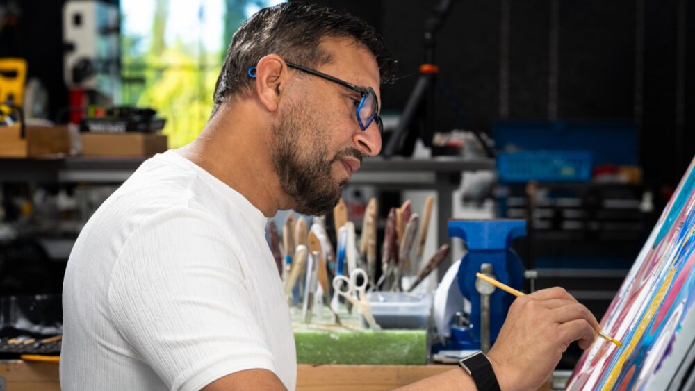 Side profile of Dr. Ali painting at a canvas in his studio.
