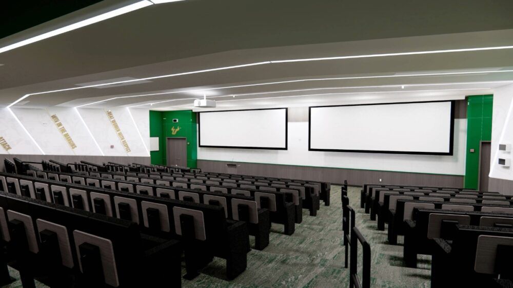 Rendering of the USF Football team meeting room with theater-style seating and Bulls branding.