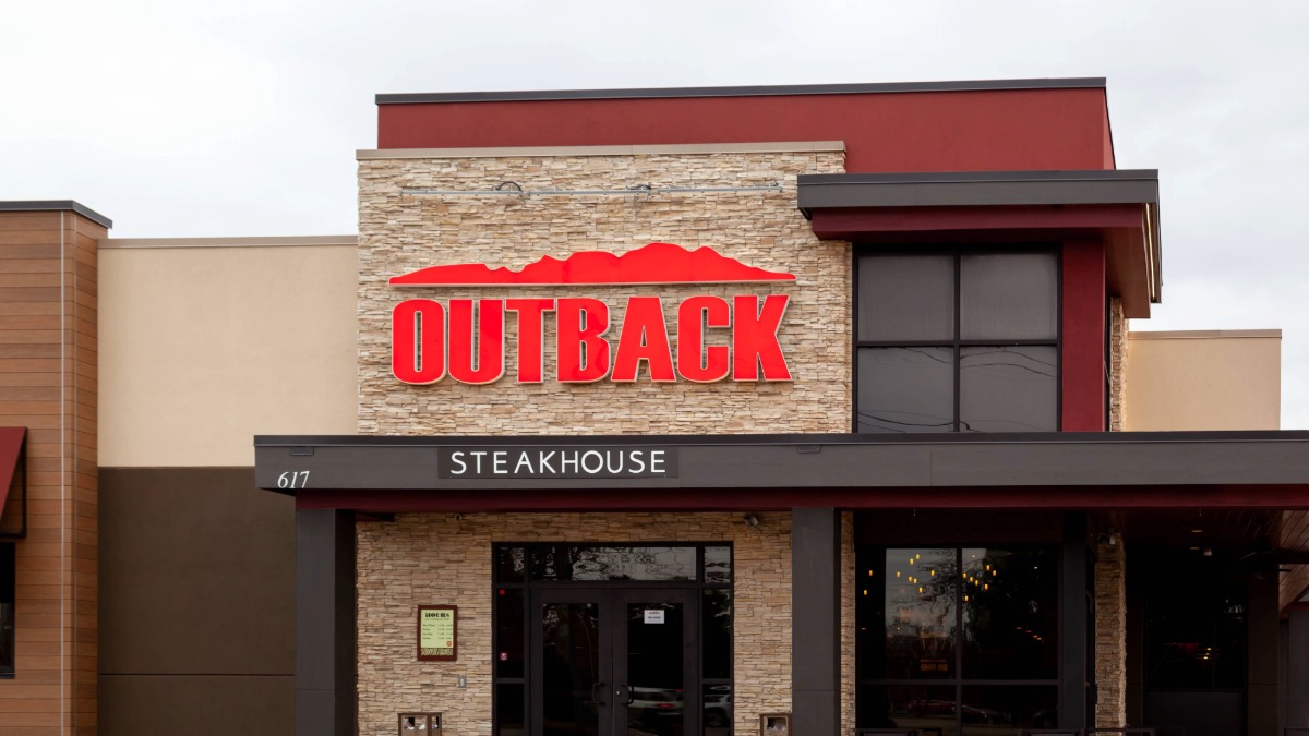 Exterior of Outback Steakhouse restaurant with red logo and stone facade