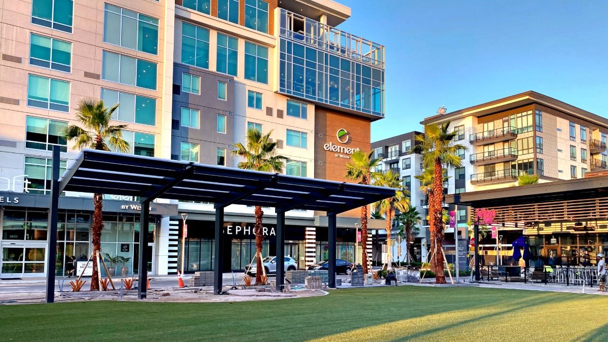 People gathering on the lawn at Midtown Commons surrounded by restaurants and shops in Midtown Tampa