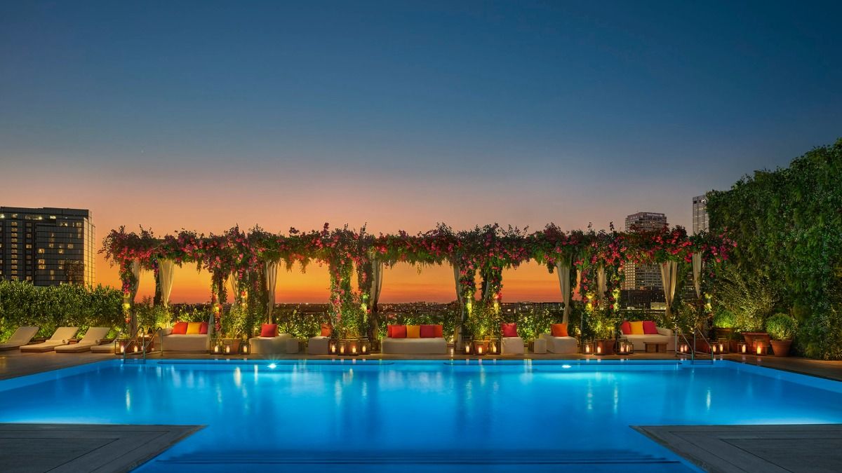 Rooftop pool at The Tampa Edition at sunset, overlooking Water Street with floral cabanas and city views