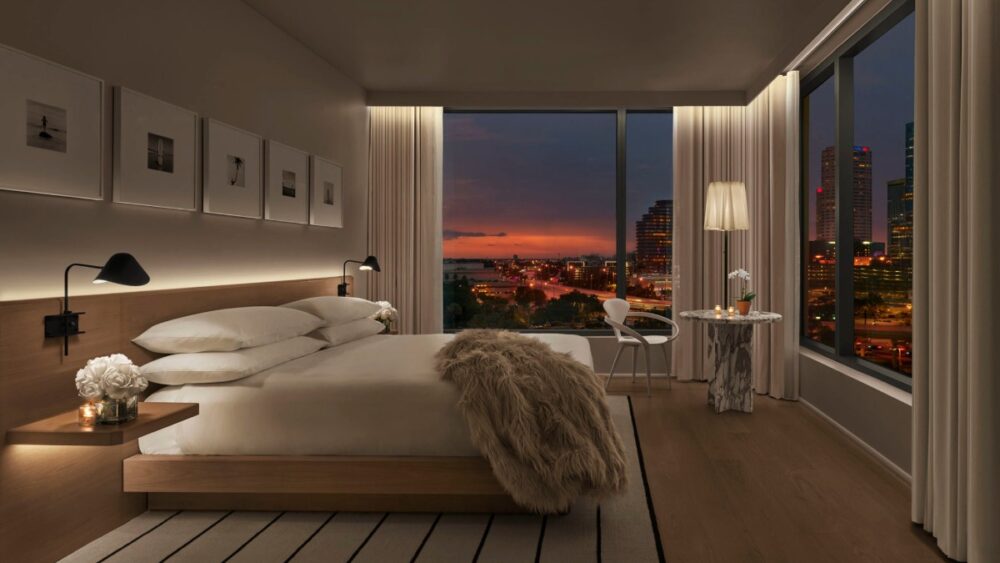 Guest room at The Tampa Edition with minimalist décor, floor-to-ceiling windows and a view of downtown Tampa at sunset
