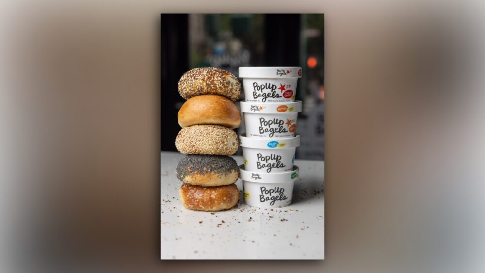 Stack of bagels beside PopUp Bagels cream cheese containers