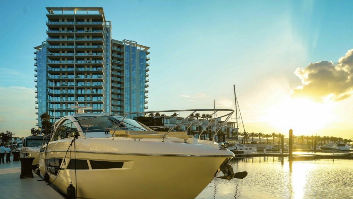 A luxury yacht docked in front of Marina Pointe’s waterfront tower at sunset in South Tampa