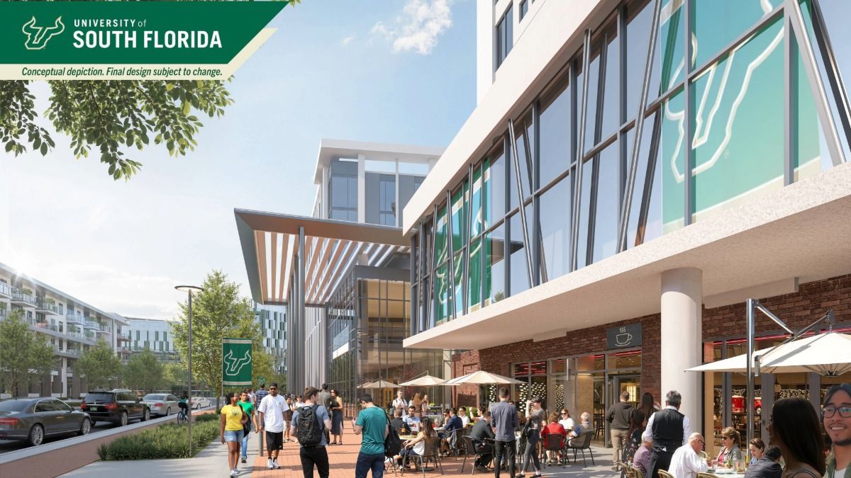 Street-level view of the USF Fletcher District with green-framed mixed-use buildings and palm-lined sidewalks.