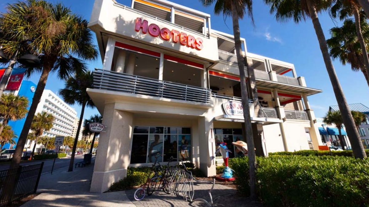 Exterior view of the Original Hooters restaurant in Clearwater, Florida, showing its multi-level building with palm trees and bikes parked outside.