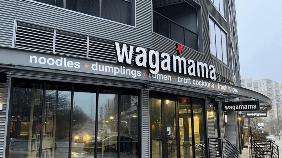 Exterior of a Wagamama restaurant with its name in bold lettering above the entrance, featuring signage for noodles, dumplings, ramen, craft cocktails and fresh juices.