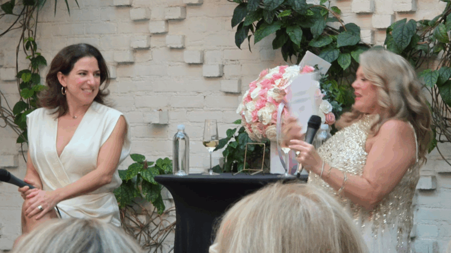 Neen James speaks with her publisher during the launch of Exceptional Experiences at Oxford Exchange in Tampa, surrounded by guests and floral décor.