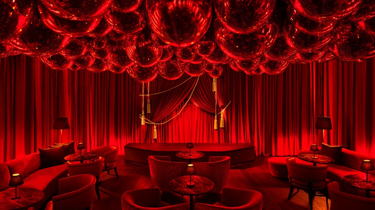 The Red Room at The Tampa EDITION glows in deep red lighting with velvet seating, mirrored disco balls covering the ceiling, and intimate tables arranged for late-night guests.