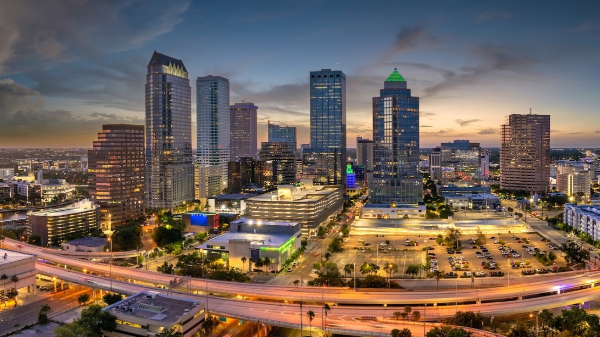 Downtown Tampa skyline at sunset, featuring illuminated buildings and the city’s major roadways.